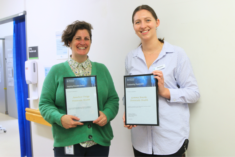 Two people standing together holding award plaques